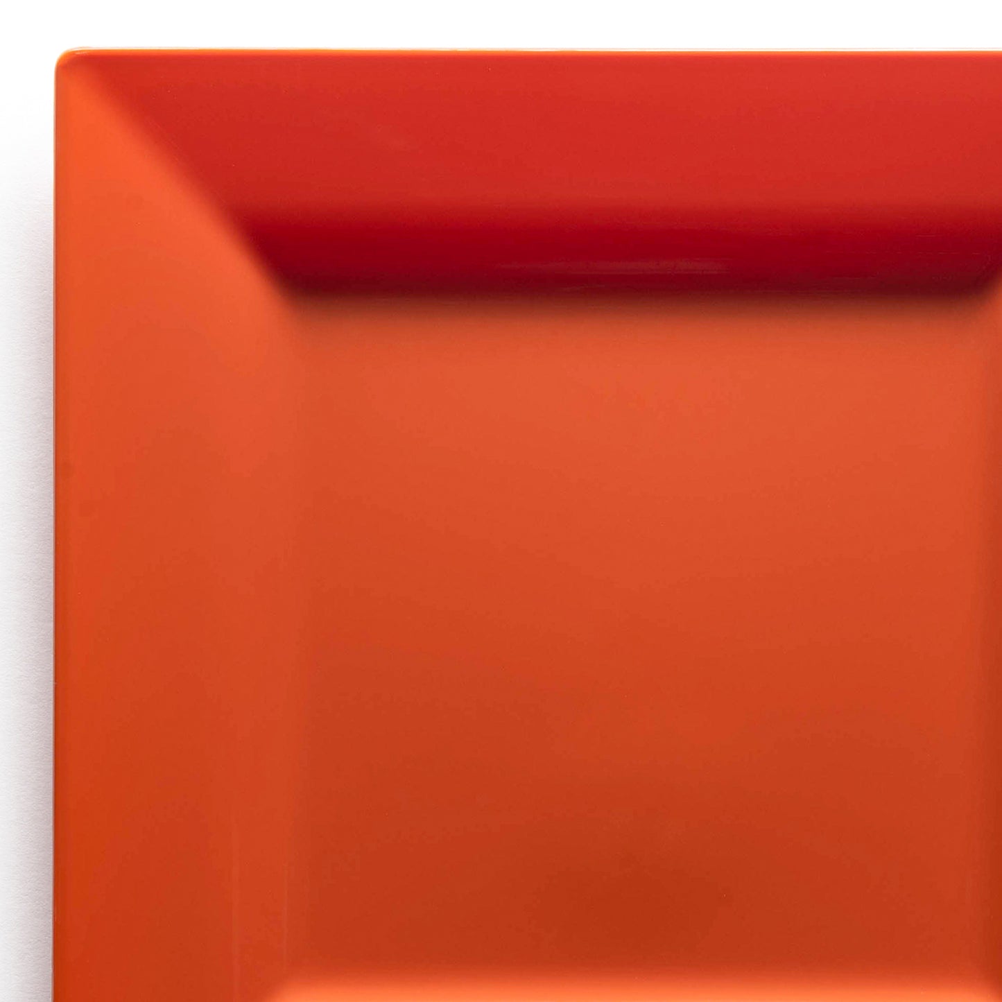A close-up shot of the Burnt Orange Square Disposable Plastic Cake Plate (6.5") with vibrant red and burnt orange gradient colors, positioned against a white background. The image captures the precise, clean lines and glossy finish of the plate's surface.