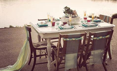 Elegant beach table setting with disposable tableware and tropical decor.