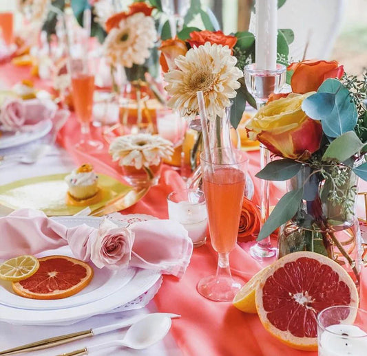 Elegant party table set with colorful disposable plates, cutlery, and decorative centerpiece.