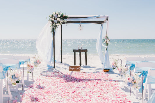 Elegant beach wedding ceremony with floral decorations.